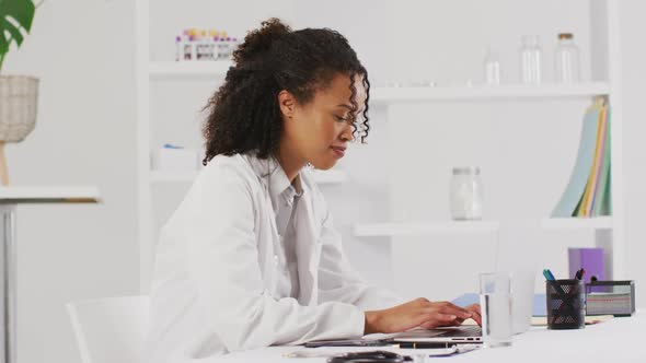 Video of portrait of smiling biracial female doctor using laptop