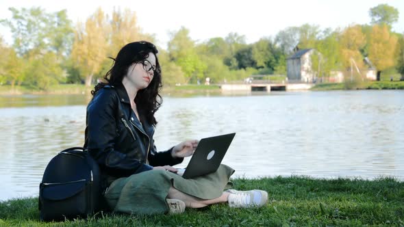 Young Girl Student Working on Laptop in the Park Near the Lake