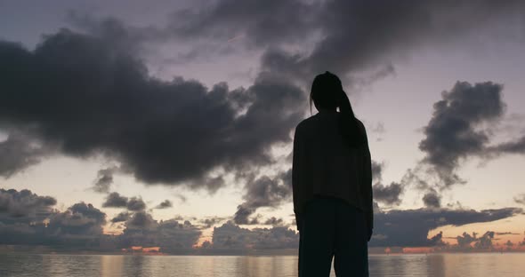 Silhouette of woman raising hand at sunrise time