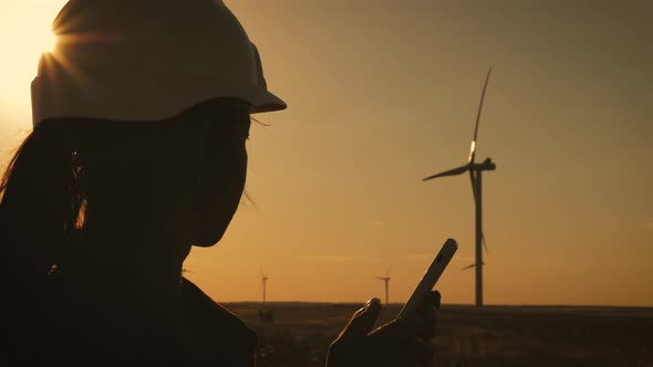 Silhouette Female Engineer Working in Wind Turbine Electricity Industrial at Sunset.