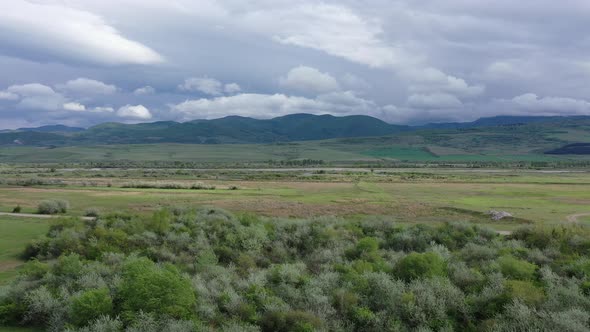 Green fields and river. Mountains are visible on the horizon