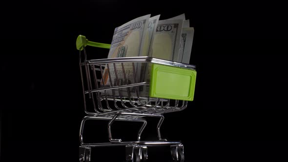 100 Dollar Bills in a Shopping Trolley Closeup Rotates on a Black Background