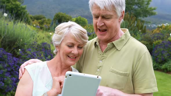 Senior couple using digital tablet in garden