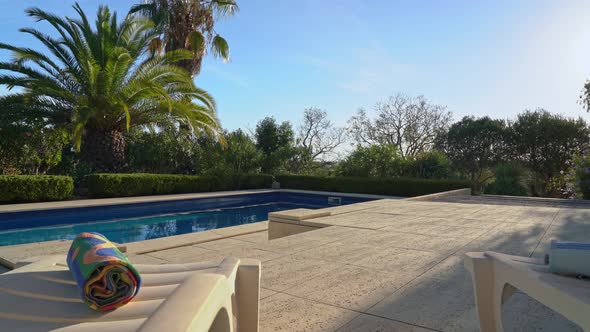 Moving Forward Through Sun Loungers and Towels Overlooking the Pool and Tropical Garden