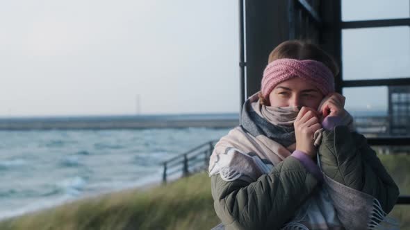 Woman in Warm Clothes Wraps Up in the Scarf at the Winter Sea Beach