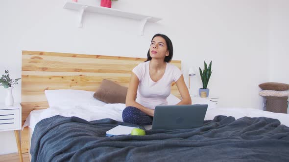 Сheerful Young Woman Working at Home Using Laptop in Bed in the Morning