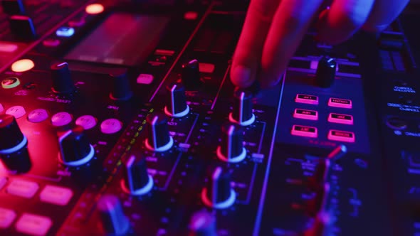 Sound engineer adjusts sound on mixing console at disco, closeup. DJ turns knobs and presses buttons