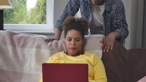 Busy Young Confident African American Woman Messaging Online As Man Supporting Wife Tapping Shoulder