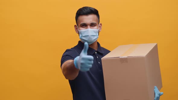 Young Man with Face Mask and Gloves Holding Package and Showing Thumb Up