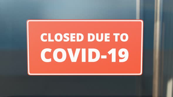 Closed due to COVID-19. Zooming in red close sign on the glass front door. 4K HD