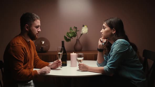 Romantic Young Couple Talking Laughing and Enjoying Sitting Together at Dinner Table in Dark Room