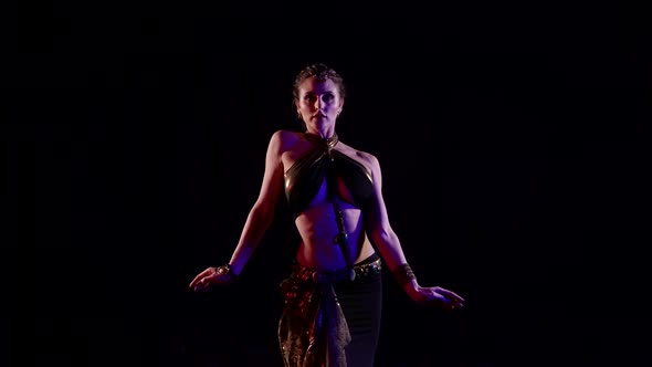 A Woman Dances an Oriental Dance on a Black Background in the Studio Makes Beautiful Hand Movements