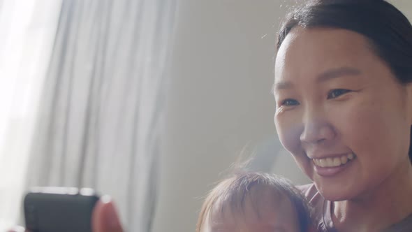 Asian Mother and Baby Daughter Taking Selfie with Phone