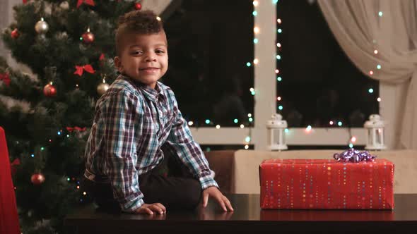 Boy Unwrapping Gift on Table.