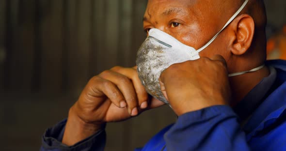 Worker removing mask in foundry workshop 4k
