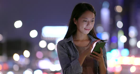 Woman using cellphone in city of Taipei at night