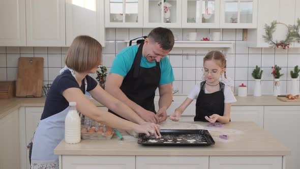 Family Putting Raw Cookies on a Baking Sheet