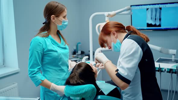 Dentist with assistant treat patient's teeth