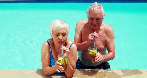 Senior couple interacting with each other while having glasses of iced tea