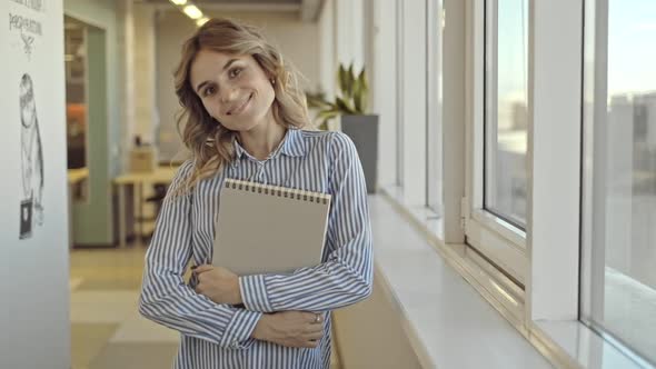 Portrait of Business Lady Posing Holding Notebook in Hand in Office Room