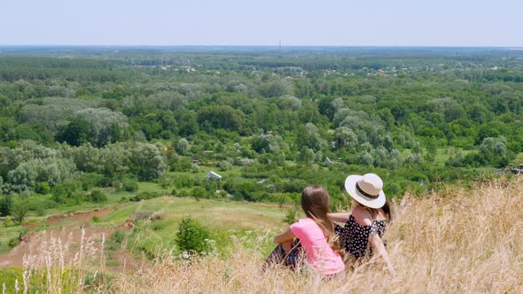 Beautiful Summer Landscape. Woman and Little Girl, Mom and Daughter, Sit on the Edge of Cliff and