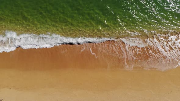 Aerial View Close-up Low Flight Over Sea Waves Rolling on the Golden Sandy Coast. Calm Surf Behind