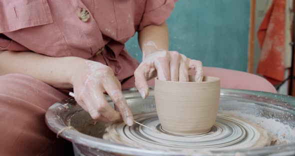 Female Potter Sitting and Makes a Cup on the Pottery Wheel. Woman Making Ceramic Item. Pottery