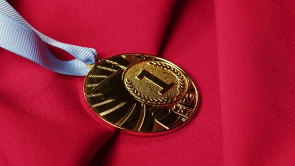 Gold Medal with Ribbon on Red Background Closeup