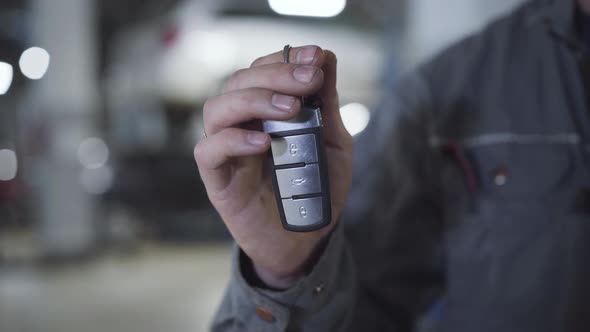 Close-up of Male Caucasian Hand Holding Car Keys. Adult Man in Workwear Showing Key From Broken