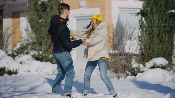 Wide Shot of Funny Couple Dancing in Snow on Winter Backyard