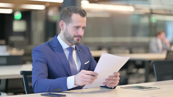 Successful Middle Aged Businessman Celebrating on Documents