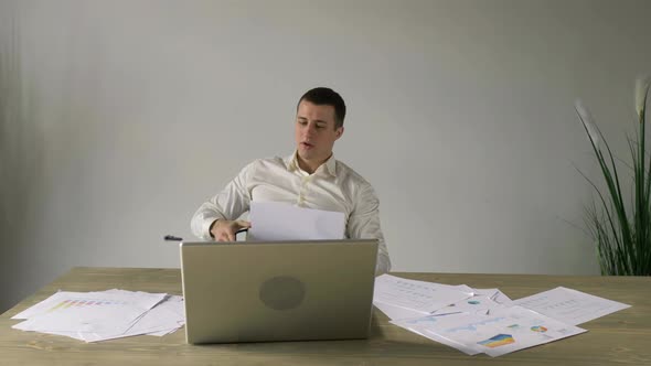 stressful businessman throws off paper documents and laptop from the table