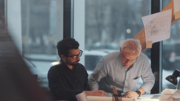 Mixed-Aged Male Architects Discussing Construction Plan in Office