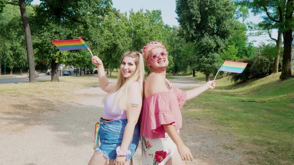 Blond man and woman waving rainbow flag in park