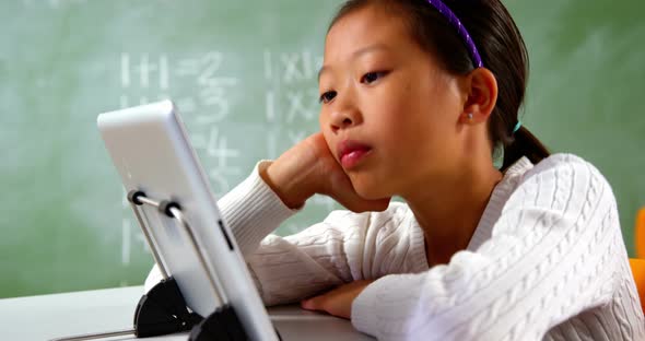 Schoolgirl using digital tablet in classroom at school