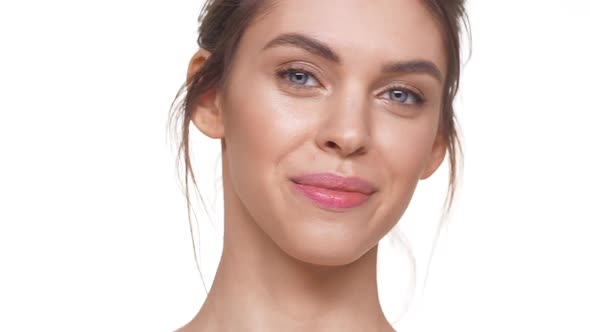 Smiling Beautiful Caucasian Girl Looking at Camera in Slowmotion Over White Background