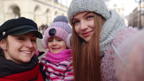 Women Tourists Taking Selfie Photos on Mobile Phone with Adoption Child Girl on Winter City Street