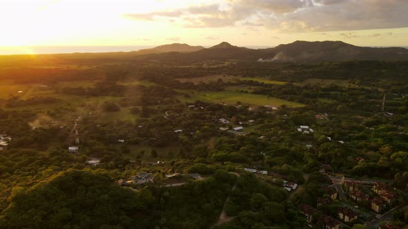 Cinematic aerial footage of a pompous mansion on a hill within the rainforest. Golden glow of the su