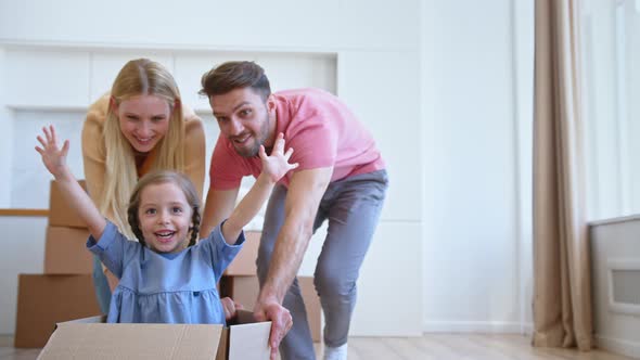 Joyful parents play with little funny daughter in blue dress moving kid