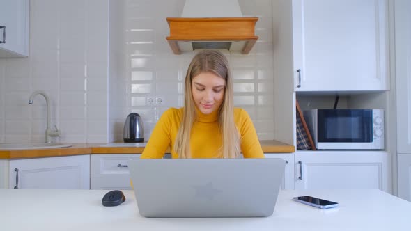 Freelancer girl with blonde hair typing text on laptop computer keyboard at home in 4k video