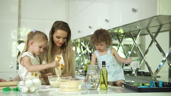 Mother With Daughters Cooking Food In Modern Light Kitchen