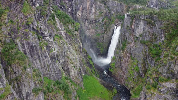 Amazing Vøringsfossen waterfall inside canyon - Aerial moving backwards - Huge amount of water falli