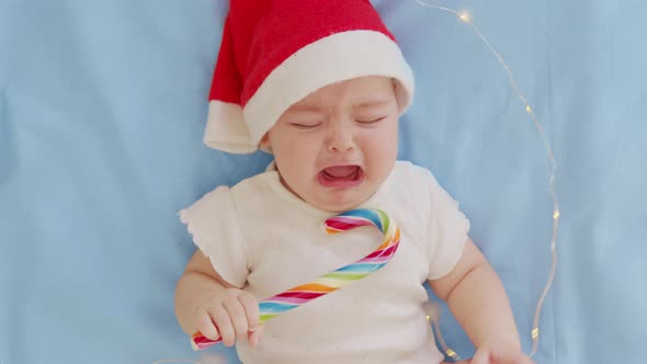 Christmas Portrait of Cute Crying Little Newborn Baby Girl Wearing Santa Hat