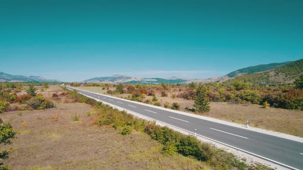 Aerial View Empty Asphalt Road on the Plateau Between Green Fields Highland Way