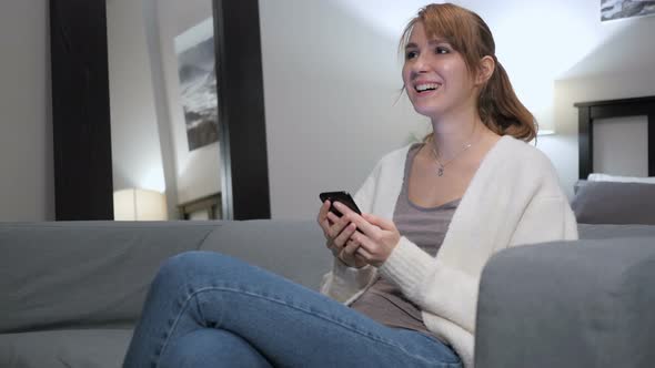 Reaction to Success by Woman Using Smartphone in Bedroom