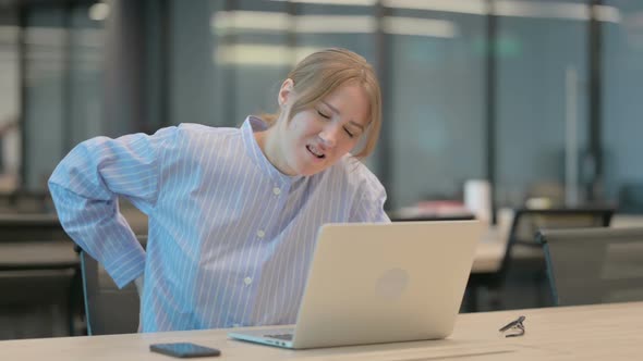 Young Woman Having Back Pain While Using Laptop in Office