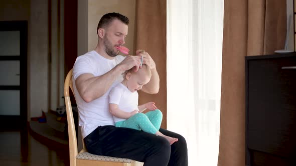 A young father spends time with a little daughter. Dad braids a ponytail