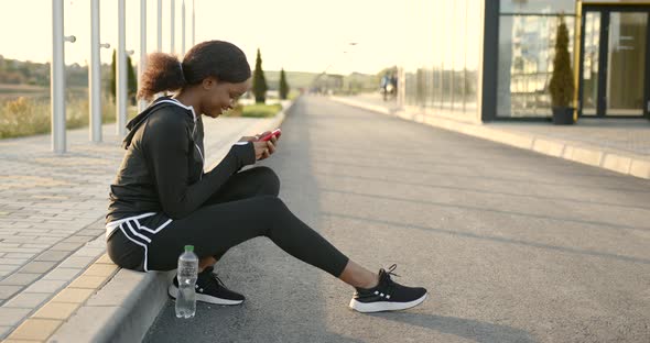 African American Woman Using Smartphone After Training