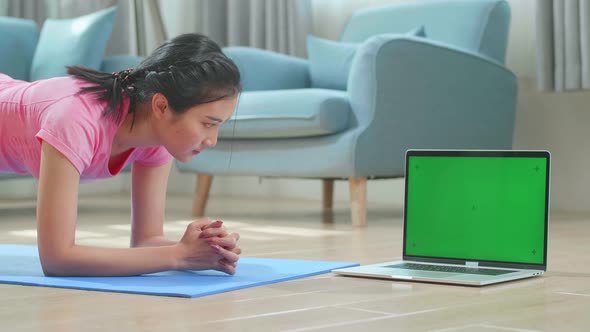 Woman Doing Yoga Plank And Watching Online Tutorials On Green Screen Laptop, Training In Living Room