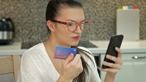 Young Woman Is at Home Transfers Money Makes Purchases with a Credit Card Through the Application